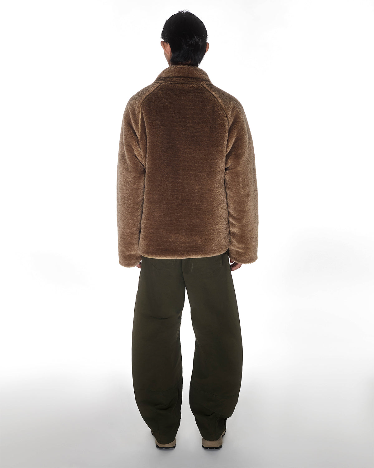 Person standing with their back to the camera wearing the Sundae School REVERSIBLE FLOWER QUILTED JEOGORI FLEECE, olive green loose pants, and beige shoes against a plain white background.