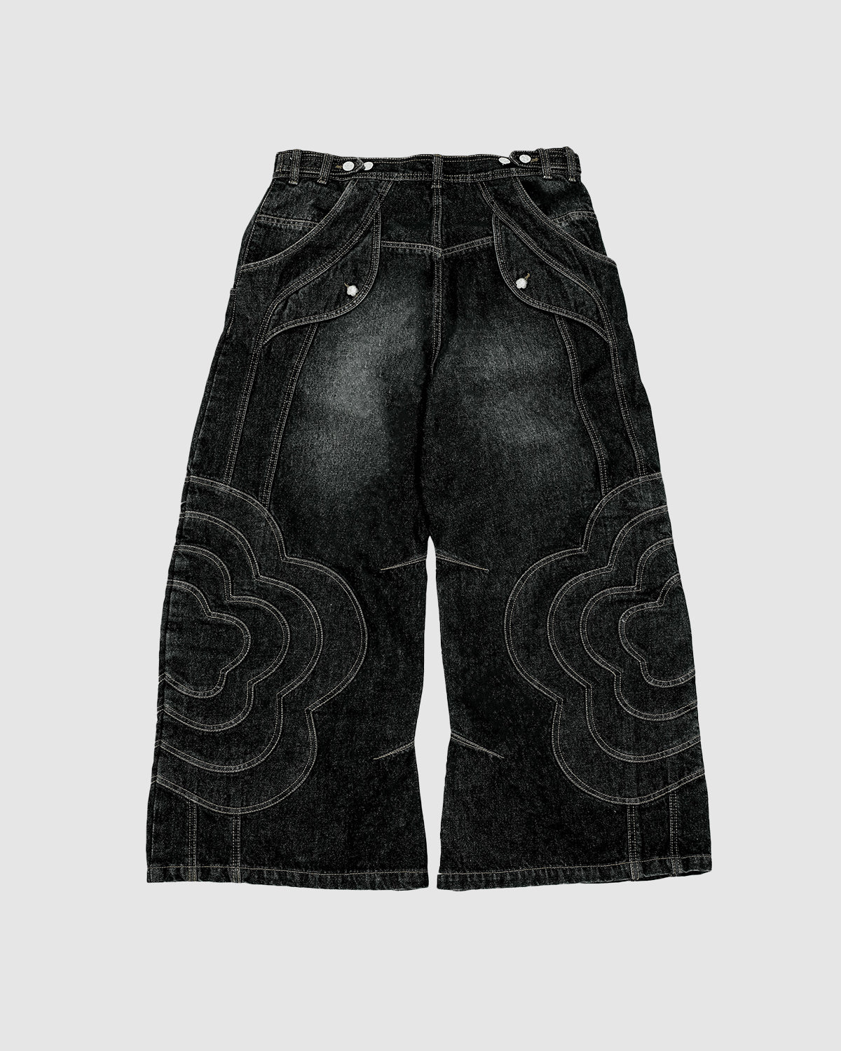 The BLACK MOCHI PANELED PANTS (x JOONIVERSE) by Sundae School are wide-leg denim jeans with bold white stitching and curved mochi flower appliqué on the legs and pockets, shown laid flat on a light gray background.