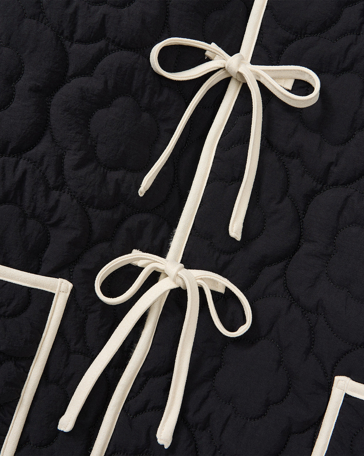 Close-up of Sundae School’s BLACK IVORY REVERSIBLE FLOWER QUILTED JEOGORI FLEECE, showing black quilted fabric with a floral pattern, cream fabric ties, and trim inspired by Korean hanbok and soft sherpa fleece.