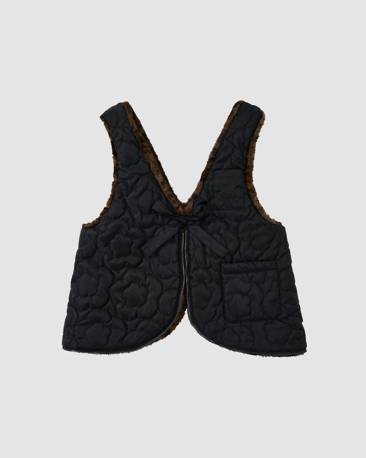 The BLACK LEOPARD BAEJA VEST / BAG by Sundae School is a sleeveless black quilted reversible vest with floral stitching, brown fuzzy lining, a front tie closure, single front pocket, shown on a plain light gray background.