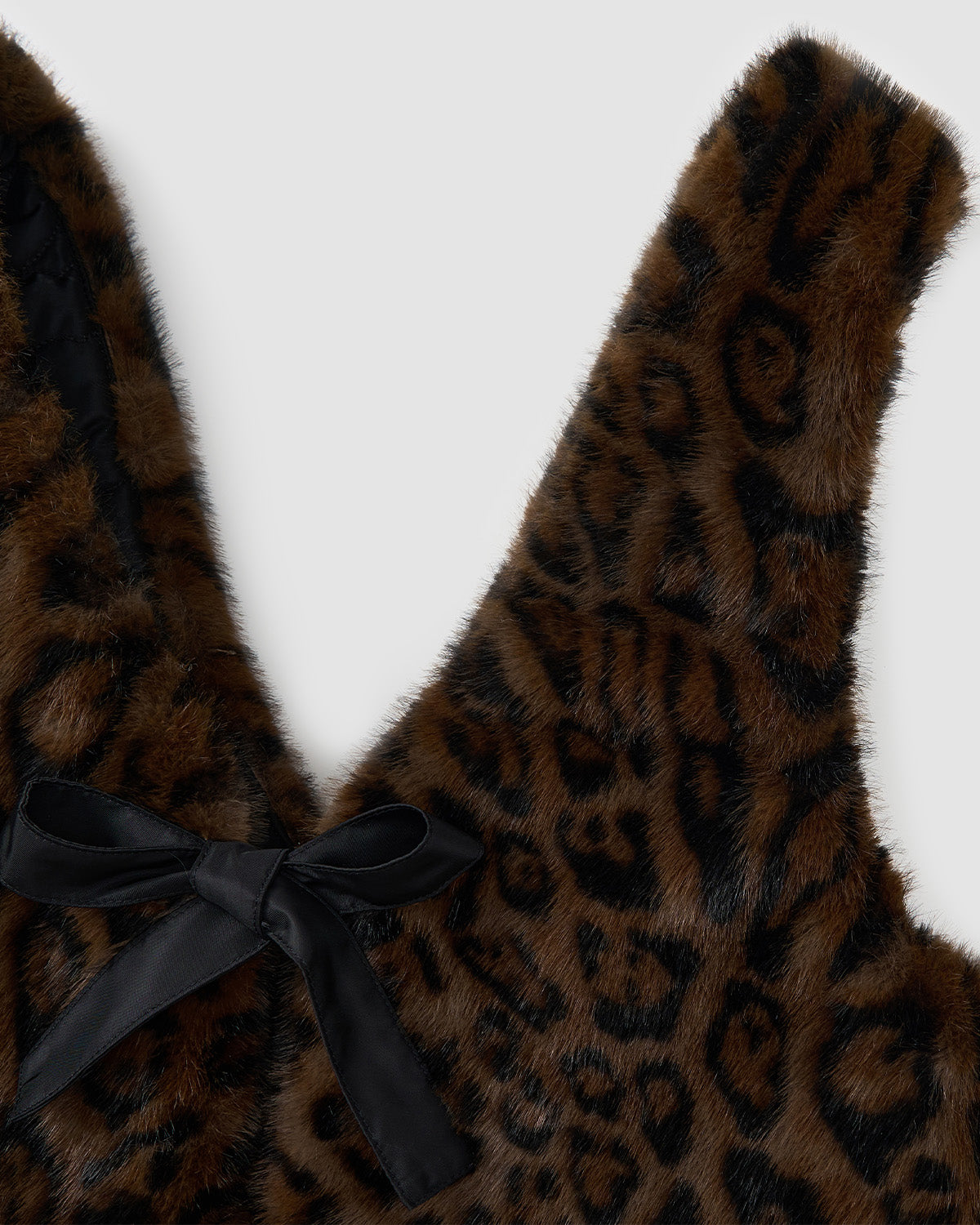 Close-up of Sundae School’s BLACK LEOPARD BAEJA VEST/BAG: brown faux fur with black leopard print and a black satin ribbon bow, inspired by traditional Korean baeja.