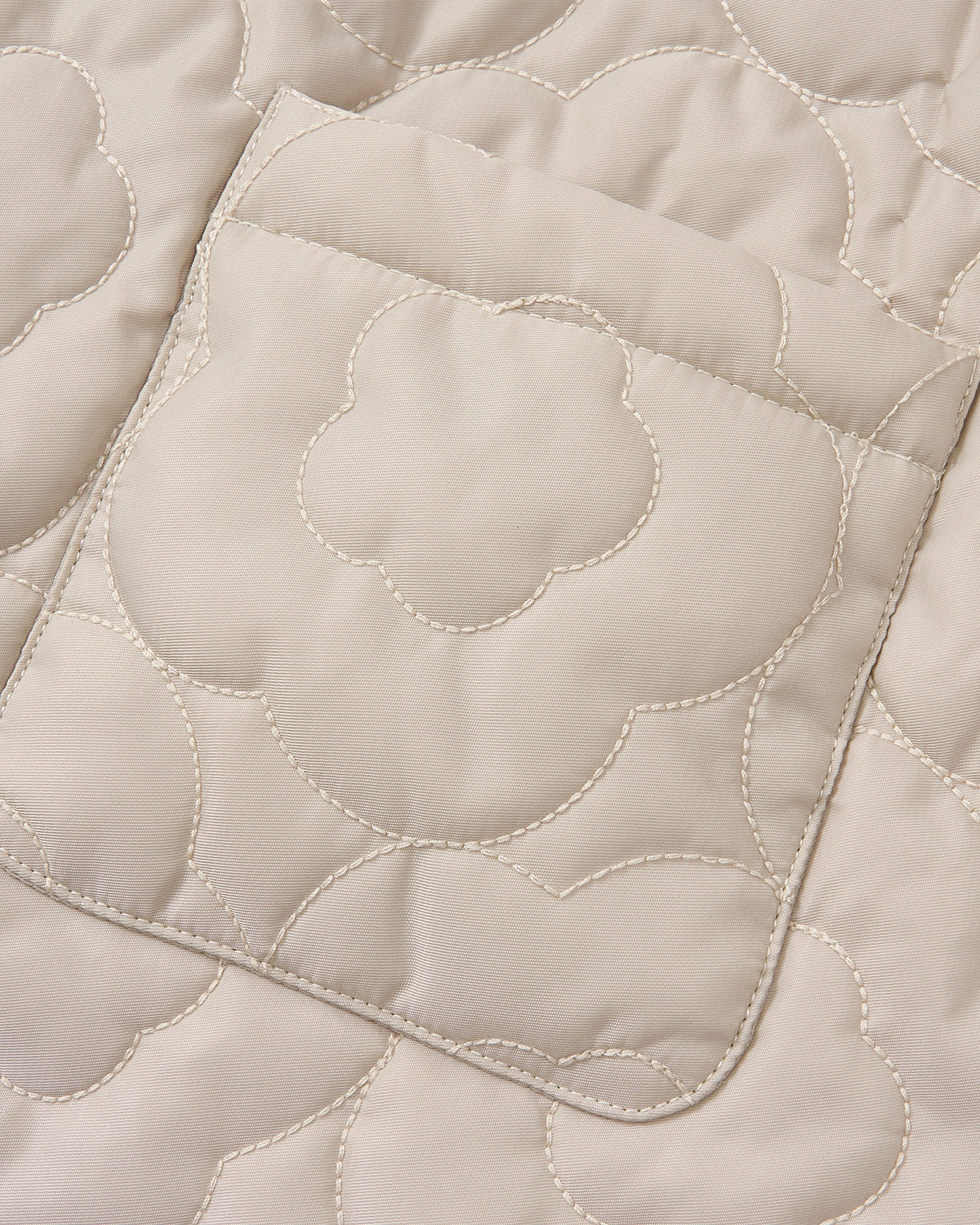 Close-up of Sundae School's SILVER PINK BAEJA VEST / BAG, featuring beige quilted fabric with a stitched floral pattern and a rectangular pocket, inspired by the traditional Korean reversible baeja vest.