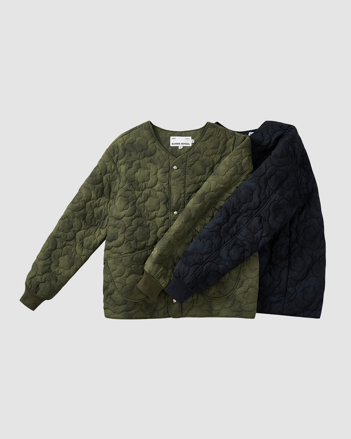 Two Sundae School BLACK MOCHI QUILTED MILITARY LINER jackets, in olive green and black, are laid flat on a light gray background. Both feature snap buttons and round necklines, inspired by a Korean military jacket style.