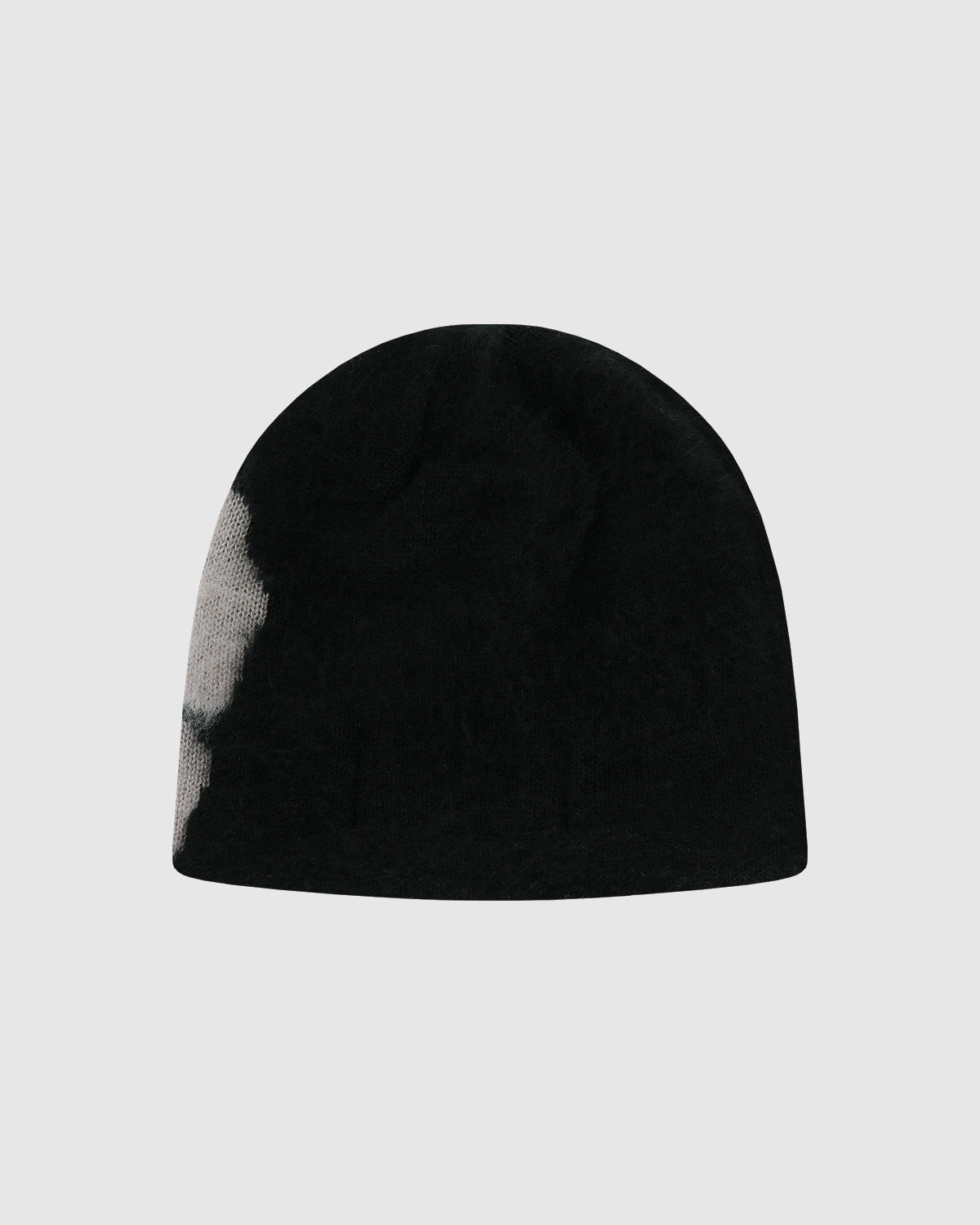 The Black Ddul Beanie by Sundae School is a black acrylic hat with a light gray patch on the left side, shown against a plain light gray background.