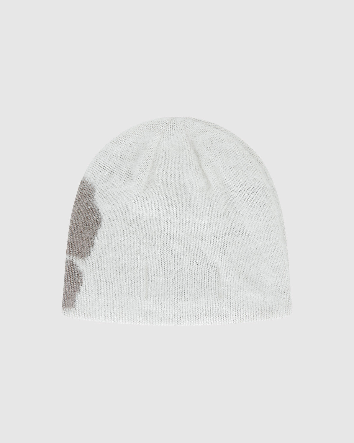 The Ivory Ddul Beanie by Sundae School is a white acrylic beanie featuring a large light gray patch on one side, shown against a plain light gray background—combining cozy style with a hint of playful protection.