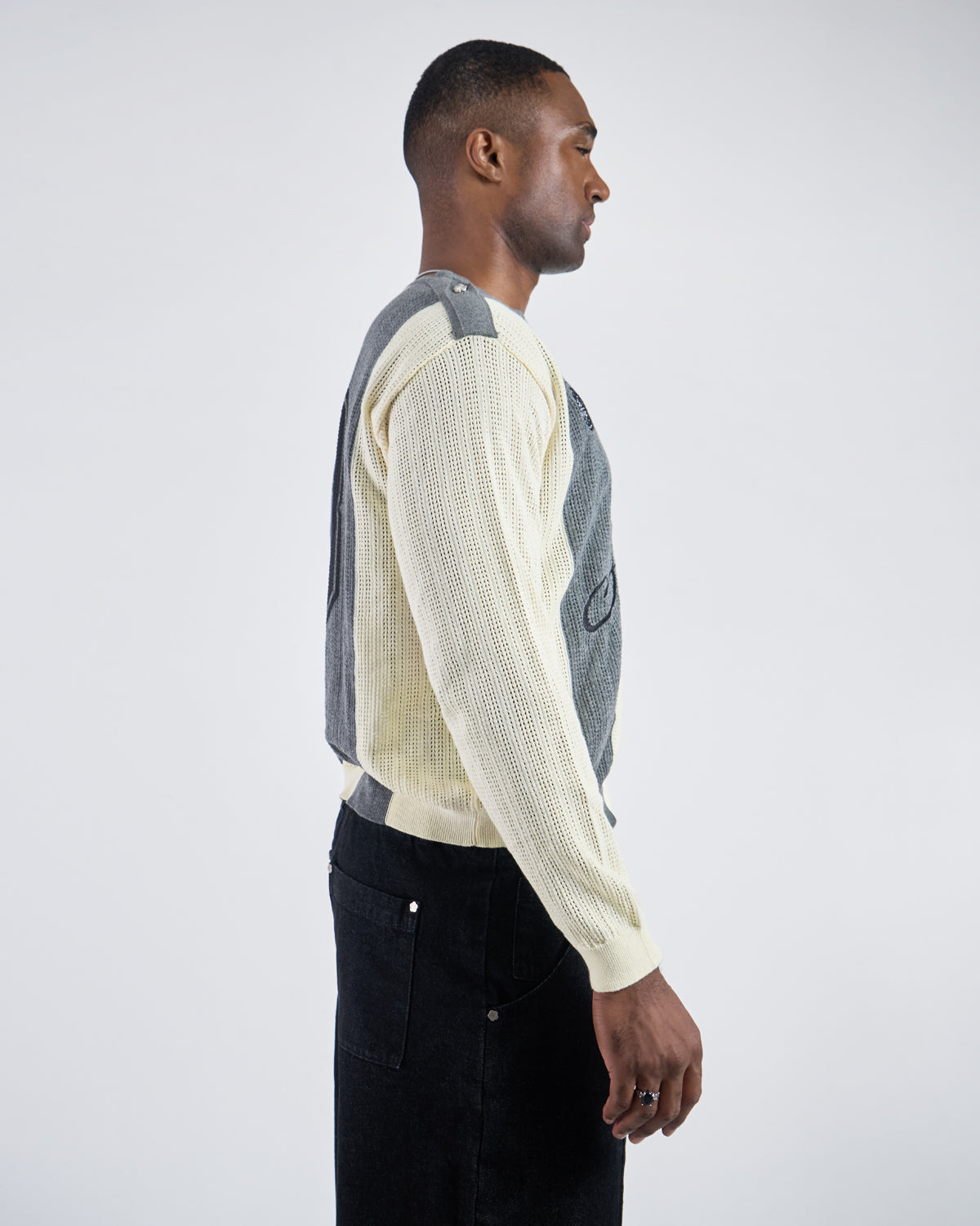 Side profile view of Butter Yellow Charcoal Sundae Soccer Jersey Knit showing relaxed fit silhouette, vertical stripe pattern continuation, ribbed sleeve construction, and overall garment drape when worn, styled with black denim pants on light background.