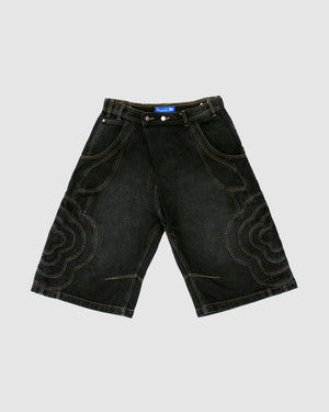 The BLACK MOCHI PANELED JORTS (x JOONIVERSE) by Sundae School are wide-leg black denim shorts with large stitched patterns, flower applique, yellow contrast stitching, and a blue label, shown laid flat on a light gray background.
