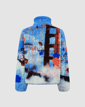 Sundae School Kloudy Bay Fleece back view showing San Francisco-inspired blue, orange, and white pattern with large central design motif, sherpa fleece construction, flat shot on light gray background.