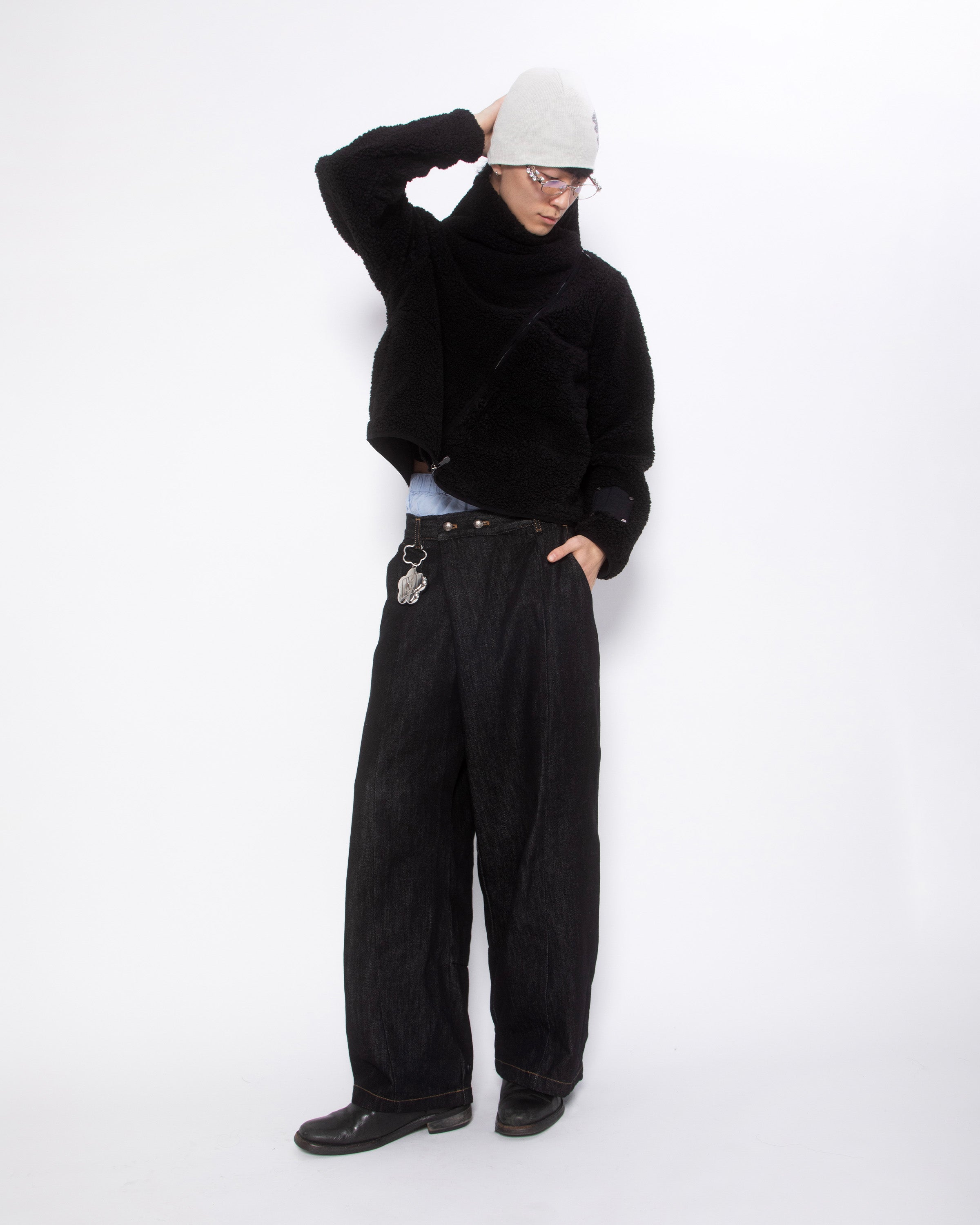 Sundae School Silver Mochi Lighter Case styled on person wearing black sherpa sweater, cream beanie, glasses, and black wide-leg jeans, case attached to belt loop with flower keychain visible, white studio background.