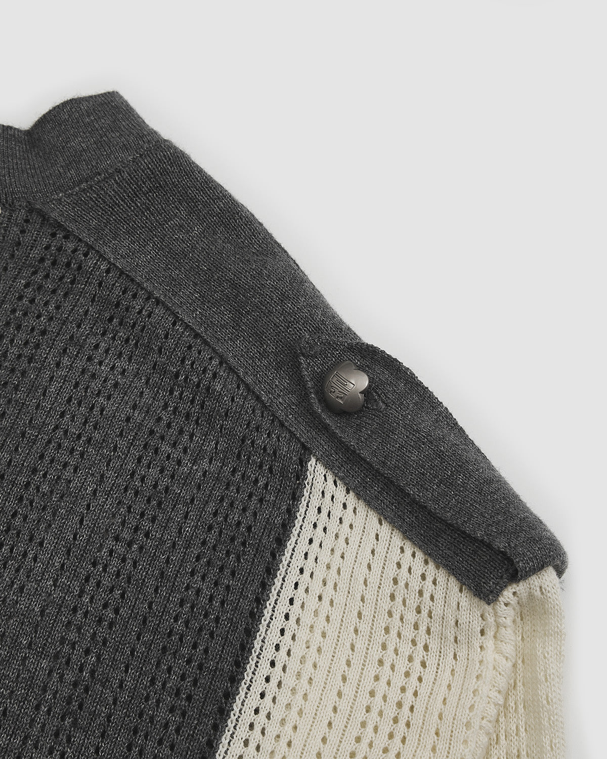 Close-up of Butter Yellow Charcoal Sundae Soccer Jersey Knit shoulder seam and snap button detail on grey knit fabric, showing construction quality and hardware finish with ribbed texture contrast between different knit sections.