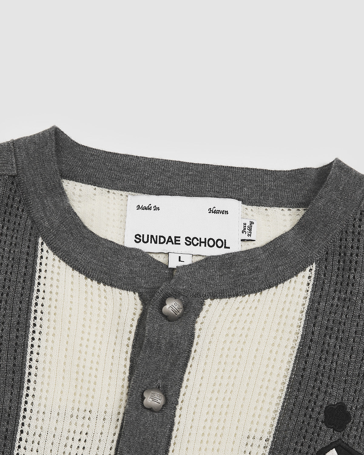 Interior neck detail of Butter Yellow Charcoal Sundae Soccer Jersey Knit showing white Sundae School brand label with black text, grey ribbed collar construction, snap button placket, and contrast knit textures between striped body and solid trim areas.