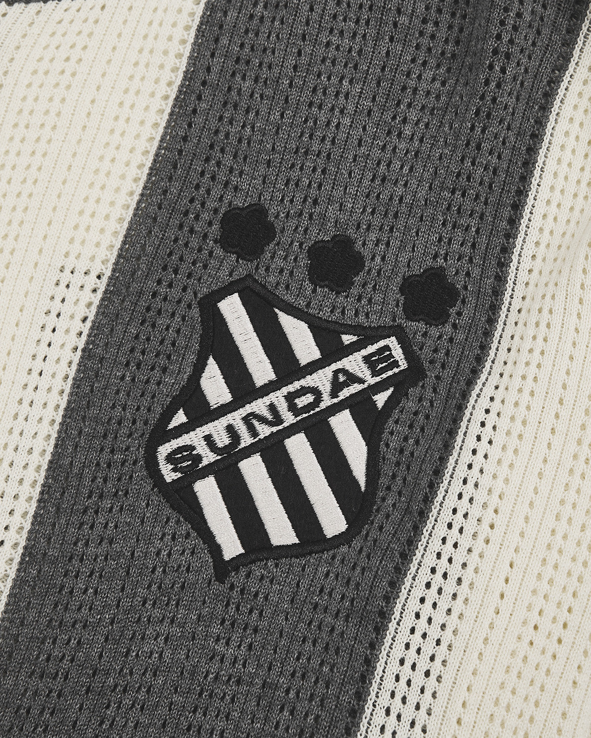 Close-up of Butter Yellow Charcoal Sundae Soccer Jersey Knit striped shield logo patch featuring