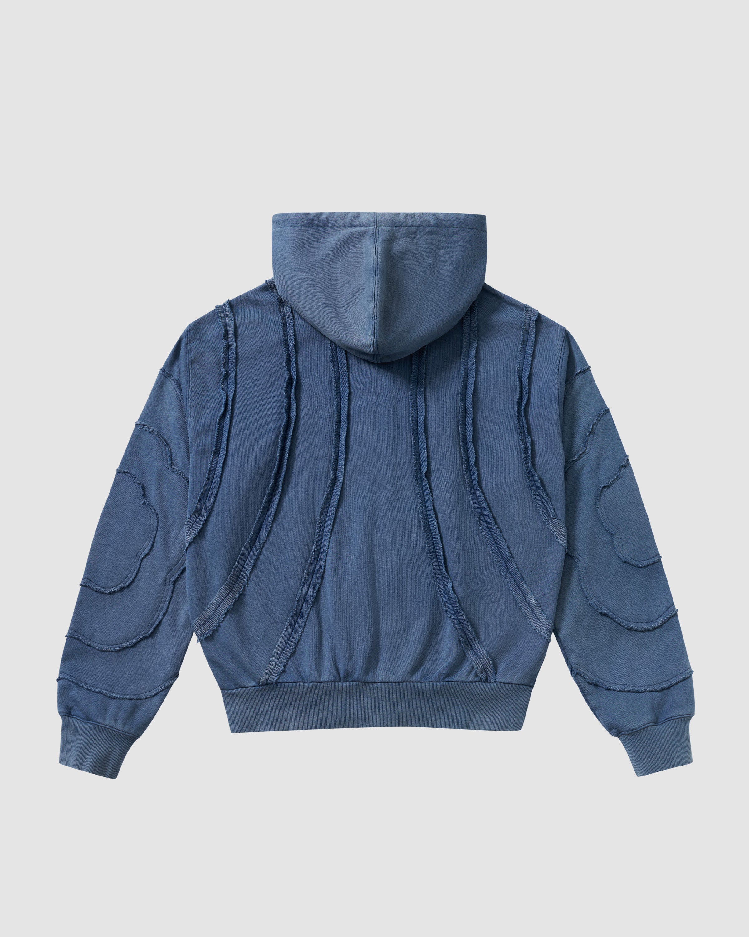 Indigo Mochi Haze Paneled Hoodie back view featuring garment washed indigo cotton with exposed curved seam details, zip-up construction, relaxed oversized fit silhouette, flat lay product shot on light background.