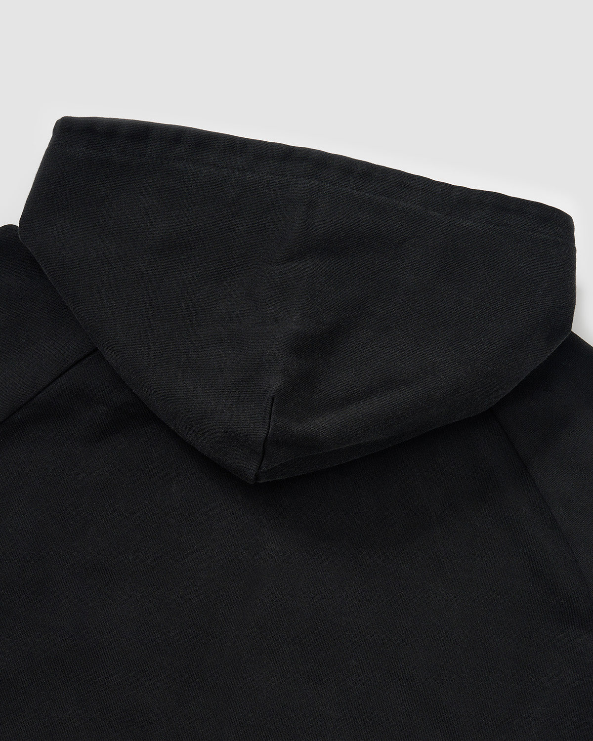 Black Fade Black Hanbok Hoodie hood shape and construction detail showing asymmetric closure design and garment washed black cotton fabric draping, flat lay on light background.