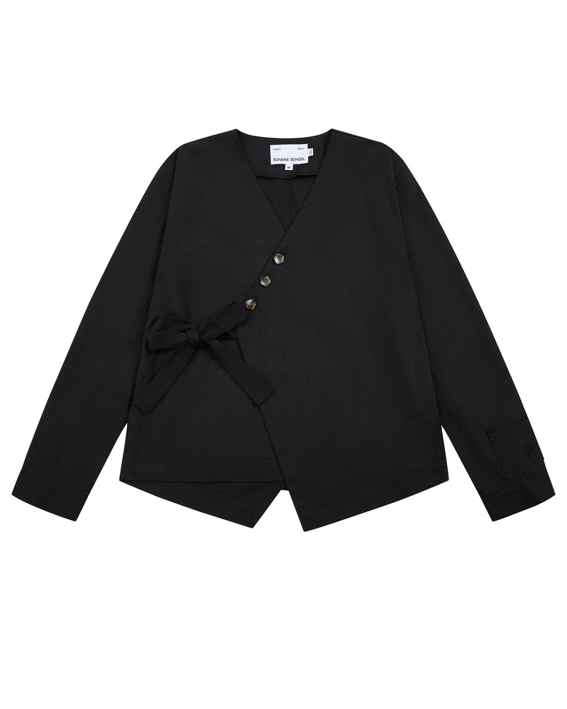 Sundae School’s BLACK HANBOK TIE BLAZER is a black long-sleeve blazer featuring a V-neckline, side tie closure inspired by the jeogori silhouette, four asymmetrical buttons, an angled hem, and a visible white tag at the neckline.