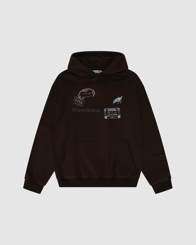 The BROWN RESILIENT HOODIE by Sundae School is a dark brown heavyweight cotton hoodie with a front pocket, travel stamp graphics, VISA stamp, barcode, chest text, and ribbed cuffs for comfort in a relaxed fit.