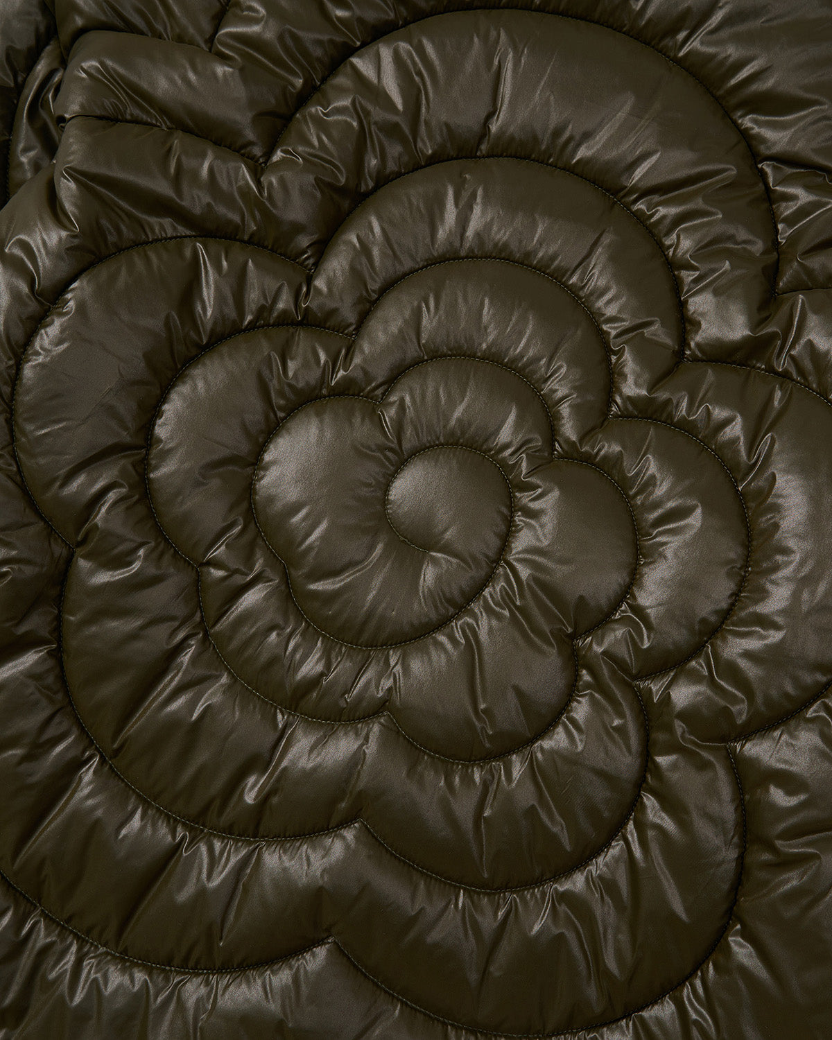 Close-up of Sundae School's OLIVE OATMEAL MOCHI SPIRAL PUFFER fabric in dark olive green, featuring a stitched floral pattern. The lightweight material looks soft, plush, and textured with a shiny finish.