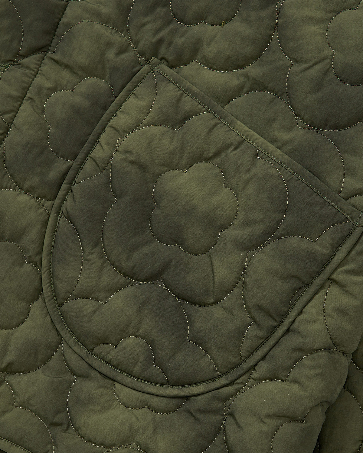 Close-up of olive green MATCHA MOCHI QUILTED MILITARY LINER by Sundae School, featuring a curved-edge pocket and floral-patterned stitching—ideal as a transitional weather layer inspired by classic Korean military jackets.
