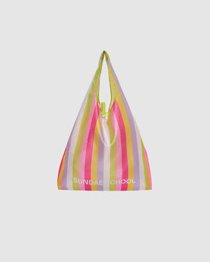 The BIG BOJAGI TOTE BAG by Sundae School is a reusable, oversized bag with pink, yellow, green, and lavender vertical stripes, a slouchy shape, top handle, and "SUNDAE SCHOOL" printed in white near the bottom. Inspired by the Korean bojagi bag.