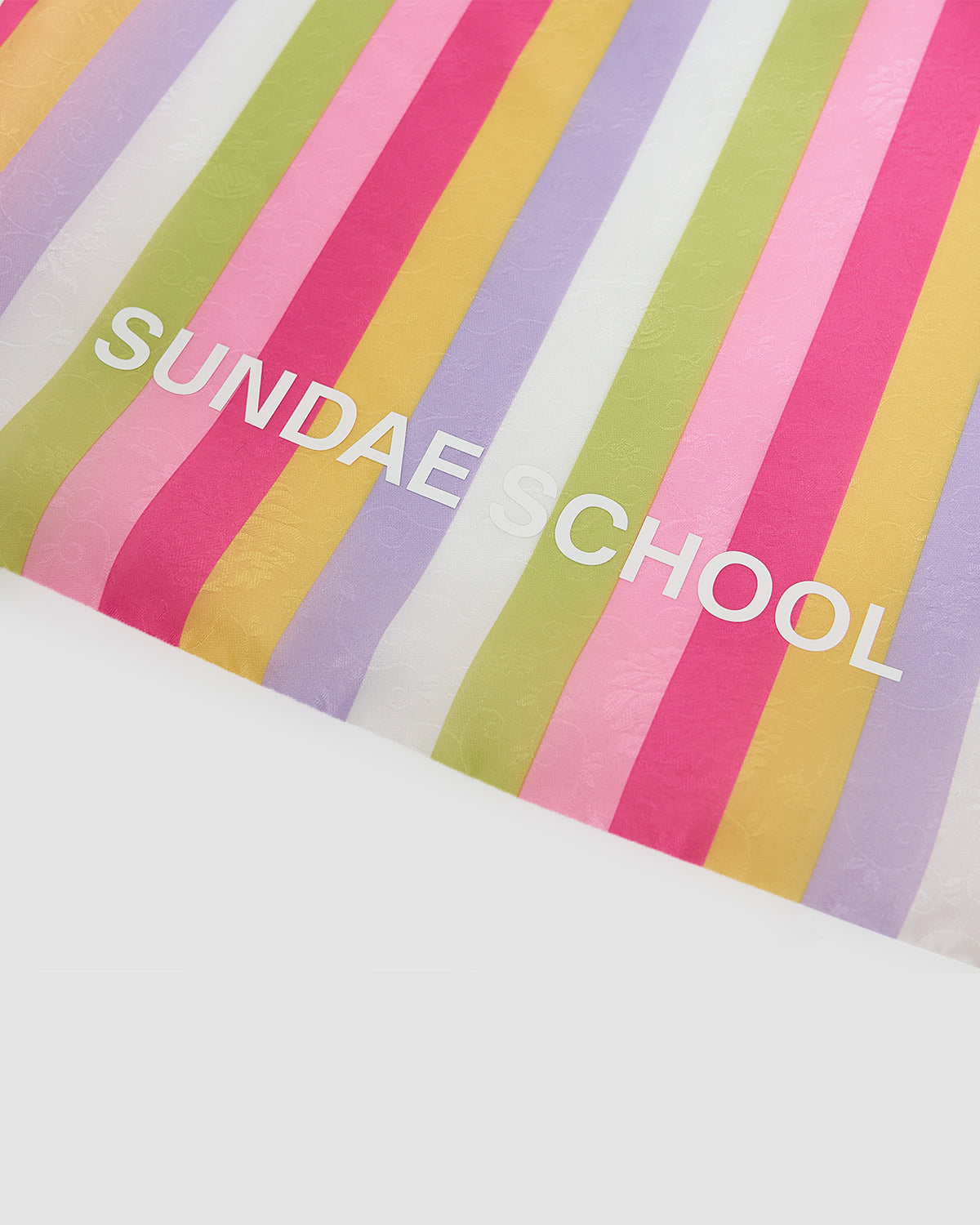 The BIG BOJAGI TOTE BAG by Sundae School features vertical pastel stripes in green, yellow, lavender, pink, and red, with 