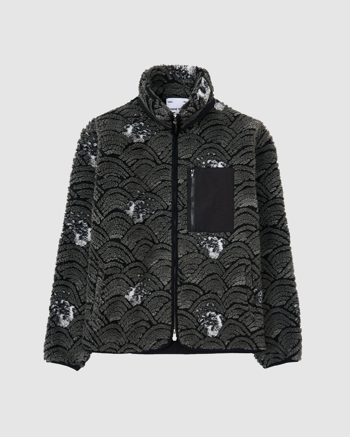 The BLACK WAVE FLEECE by Sundae School is a fuzzy dark grey zip-up jacket with a black scalloped wave jacquard pattern, high collar, and a left chest pocket, shown against a plain light background.