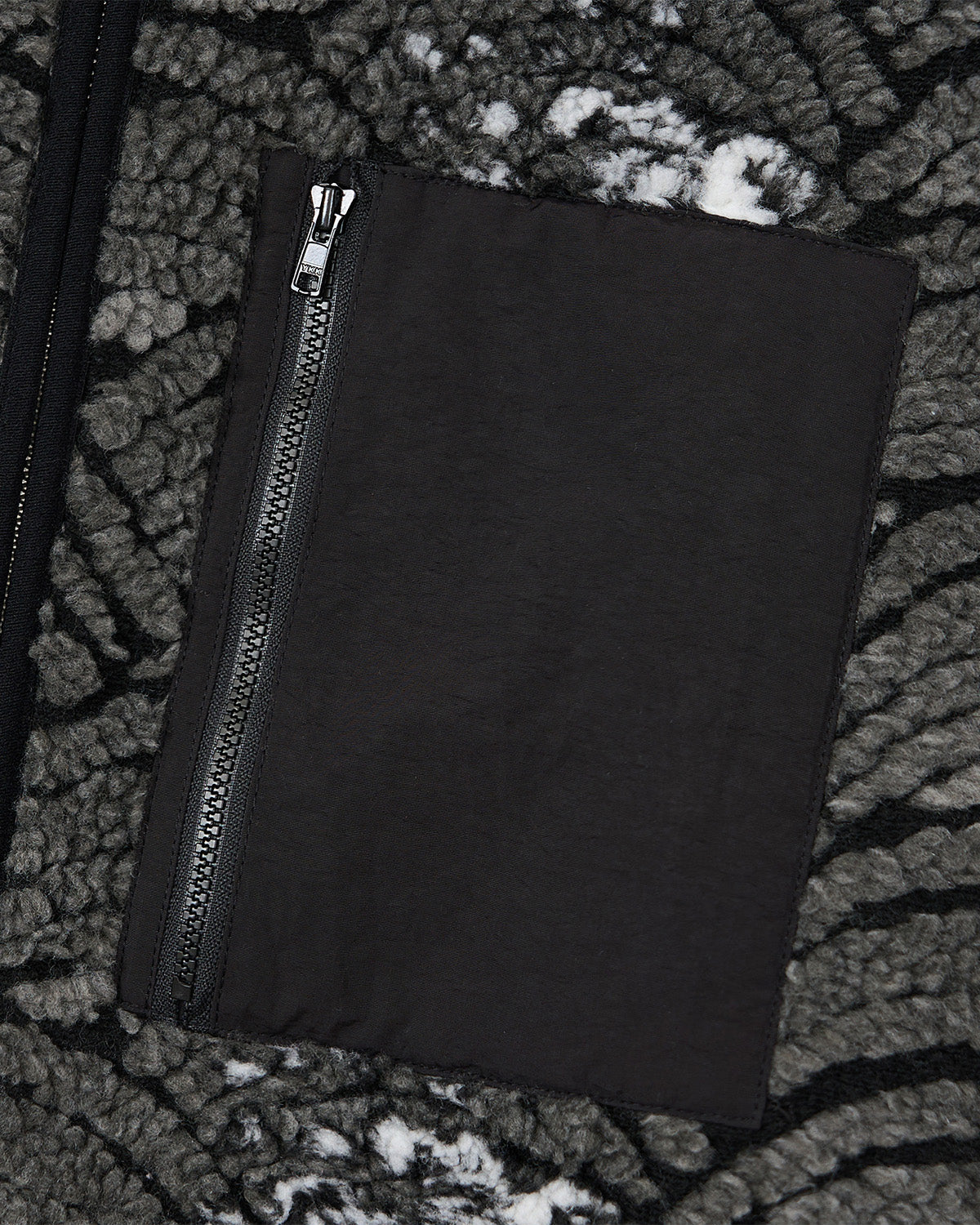 A close-up of the black zippered pocket on Sundae School’s BLACK WAVE FLEECE, featuring textured gray and black jacquard fabric with a wave motif and white speckles.