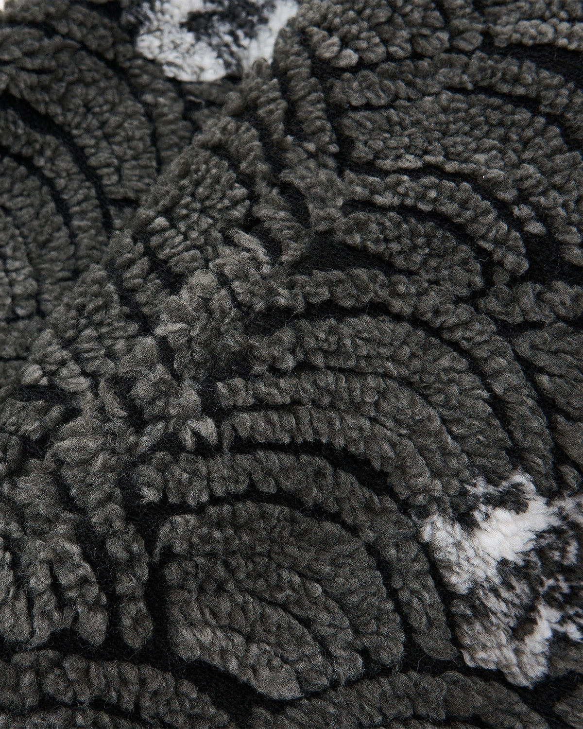 Close-up of Sundae School's BLACK WAVE FLEECE, featuring a textured, plush surface with a dark gray and black geometric wave jacquard pattern, complemented by light gray and white accents for added depth.