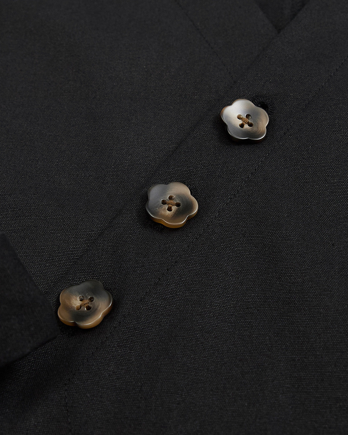 Detail view of three flower-shaped metallic buttons positioned asymmetrically on the front of the Hanbok Tie Blazer.