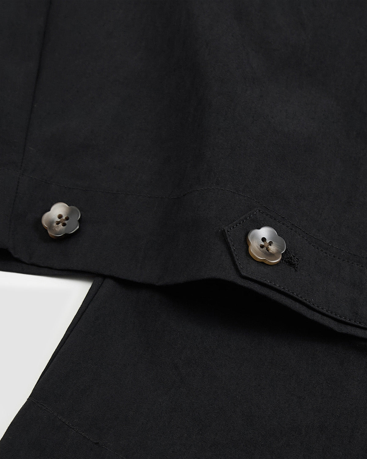Close-up of flower mochi-shaped button details at hem of Sundae School Black Pleated Nylon Pants for adjustable cinching