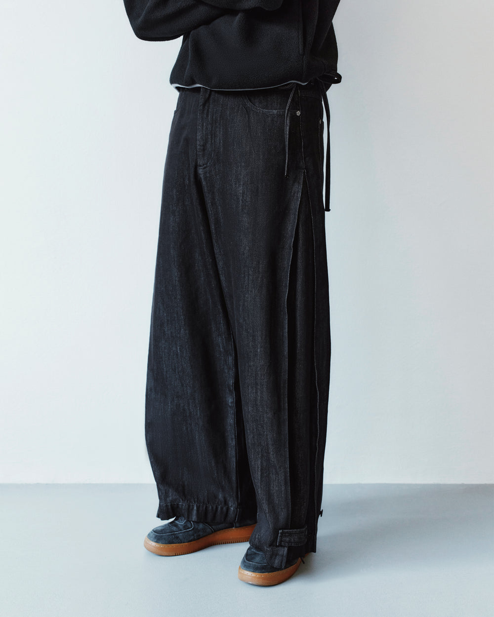 Black wide-leg BLACK ACCORDION DENIM PANTS featuring vertical side slits and a drawstring waist.