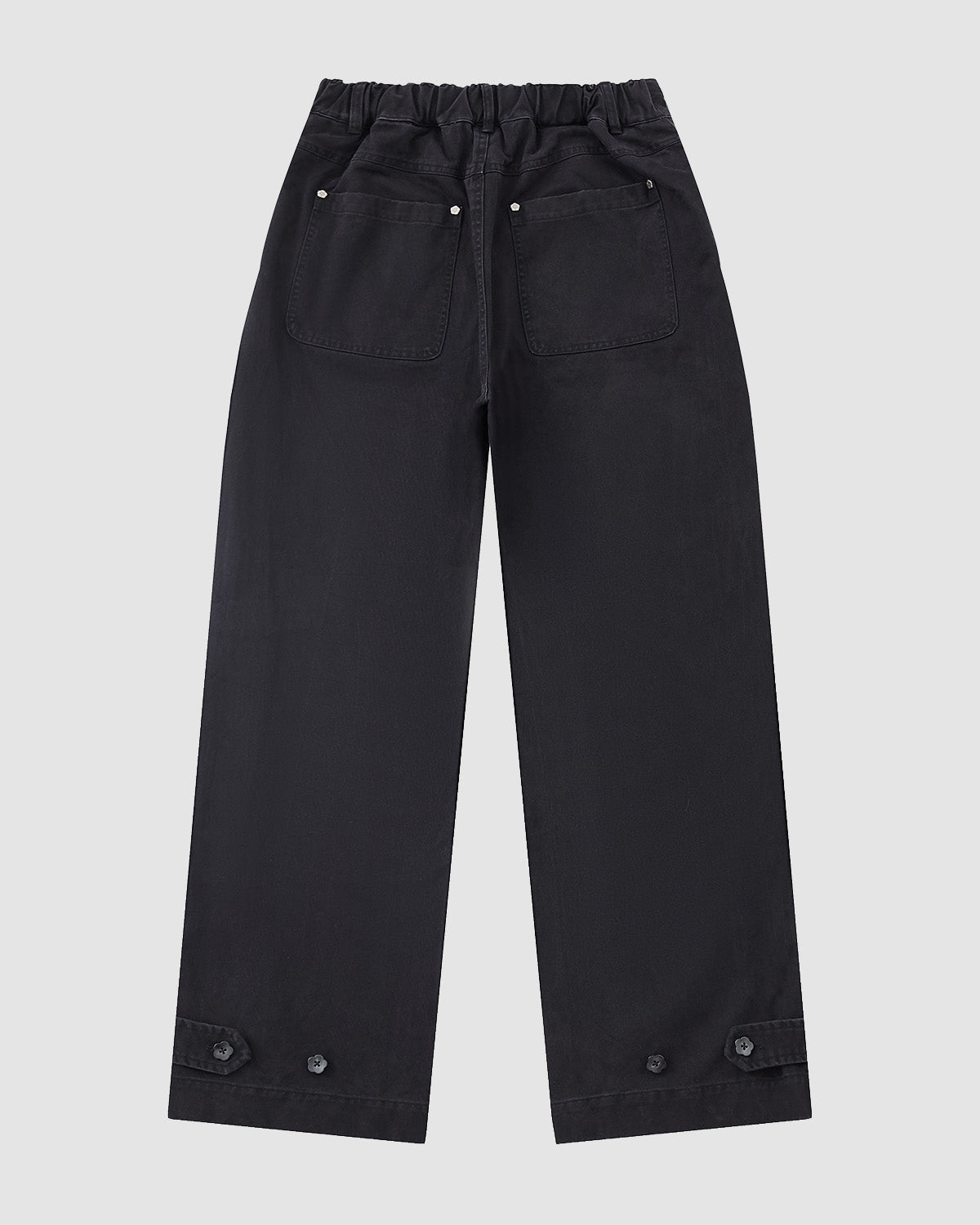 The BLACK ACCORDION CHINO PANTS by Sundae School are black, wide-leg hanbok-inspired pleated pants with an elastic waistband, two back pockets, and buttons near the hem, shown flat on a light gray background.