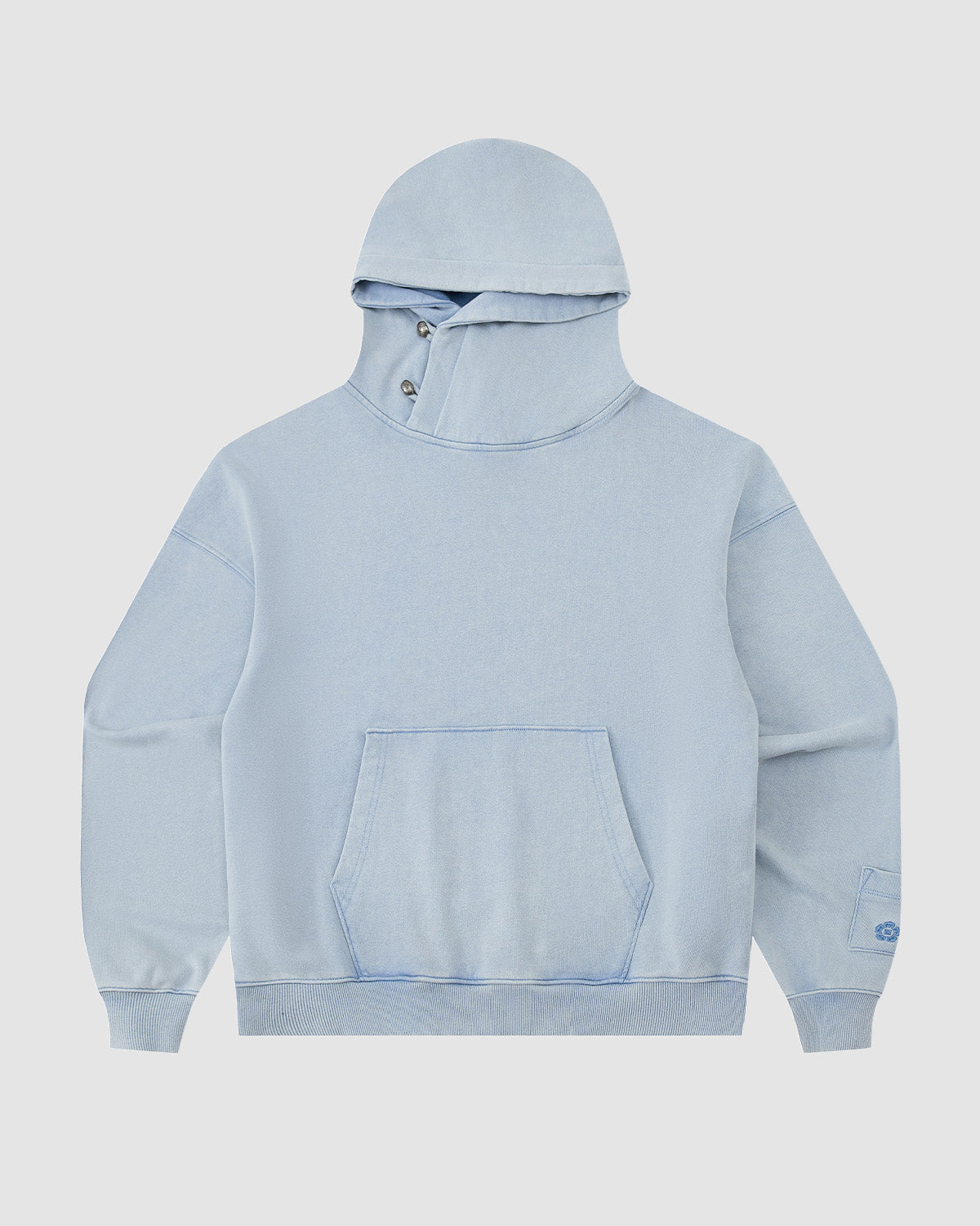 The Sundae School SKY BLUE COCOON HOODIE features an oversized hood, front kangaroo pocket, asymmetric buttoned collar, peret sleeves, and ribbed cuffs and hem, shown against a plain white background.