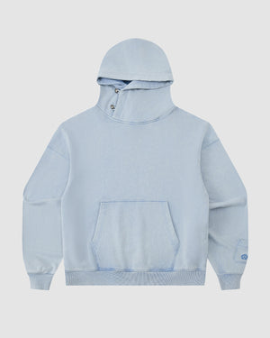 The Sundae School SKY BLUE COCOON HOODIE features an oversized hood, front kangaroo pocket, asymmetric buttoned collar, peret sleeves, and ribbed cuffs and hem, shown against a plain white background.
