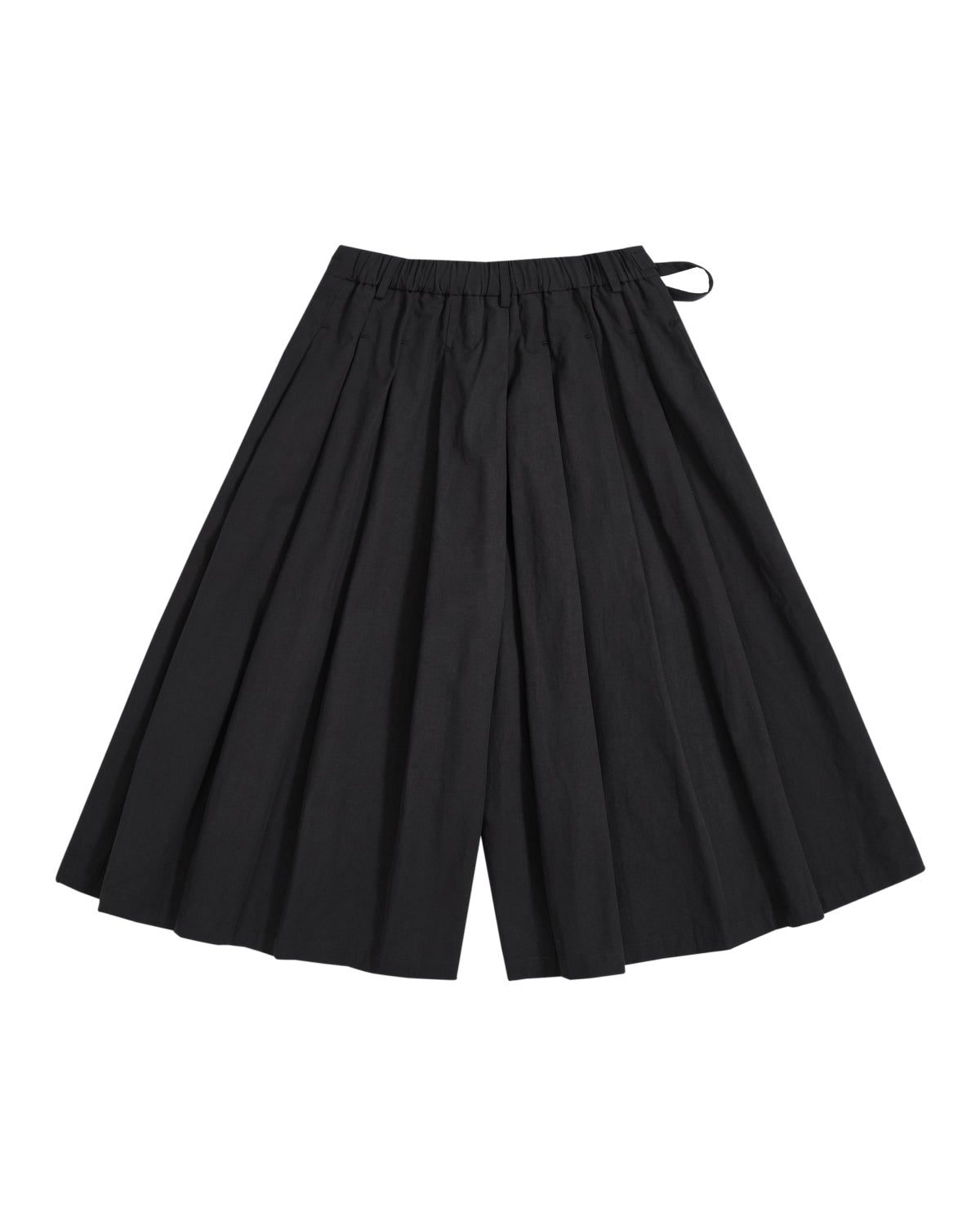 The ASYMMETRIC CHIMA CULOTTE by Sundae School is a pair of wide-legged black culottes featuring pleated detailing and an elastic waistband, designed with an asymmetric wrap pants silhouette, shown on a white background.