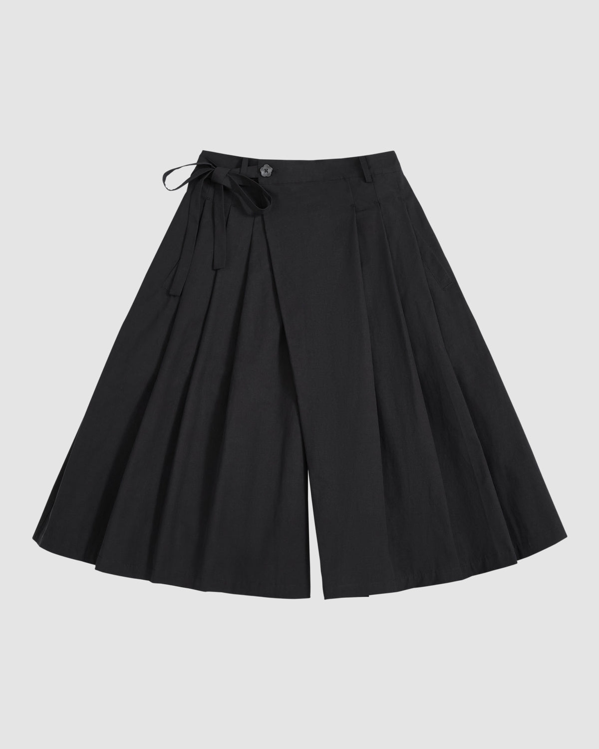BLACK PLEATED HANBOK CULOTTES by Sundae School, featuring wide legs, pleats, a button closure, and a matching fabric tie at the waist, are displayed laid flat on a light gray background.