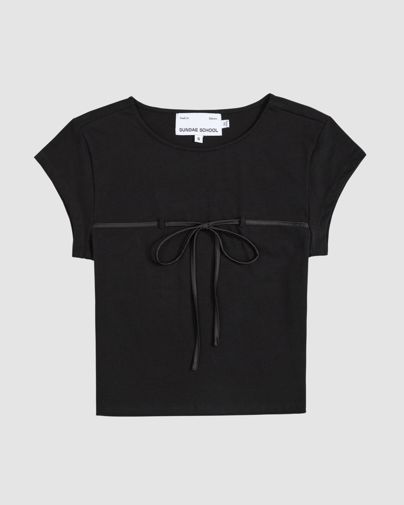 The BLACK TIE GORUM BABY TEE by Sundae School is a black, form-fitting women's top with short sleeves, a round neckline, and a thin ribbon bow across the chest. The background is light gray.