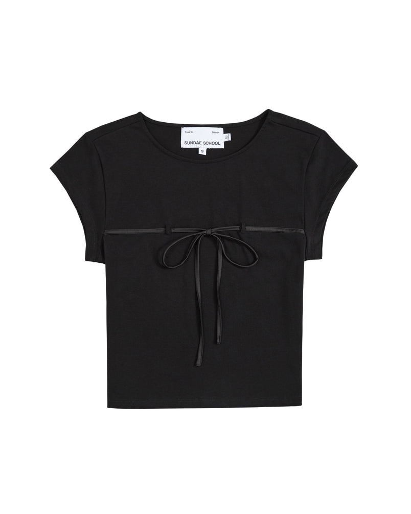 Introducing the BLACK TIE GORUM BABY TEE by Sundae School—a black cotton jersey crop top featuring short sleeves, a round neckline, and an eye-catching decorative bow at the front. Displayed flat against a white background, this form-fitting women’s shirt offers both comfort and modern style with its relaxed cropped baby tee silhouette.