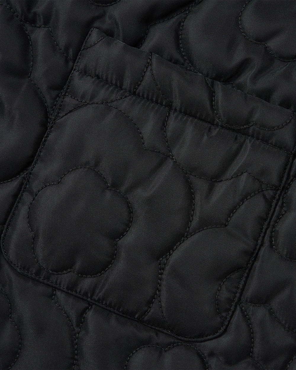 Close-up of the BLACK BAEJA VEST / BAG by Sundae School, showcasing black quilted fabric with a pocket and intricate stitching inspired by traditional Korean baeja designs. Floral and curved patterns create a textured, decorative surface.