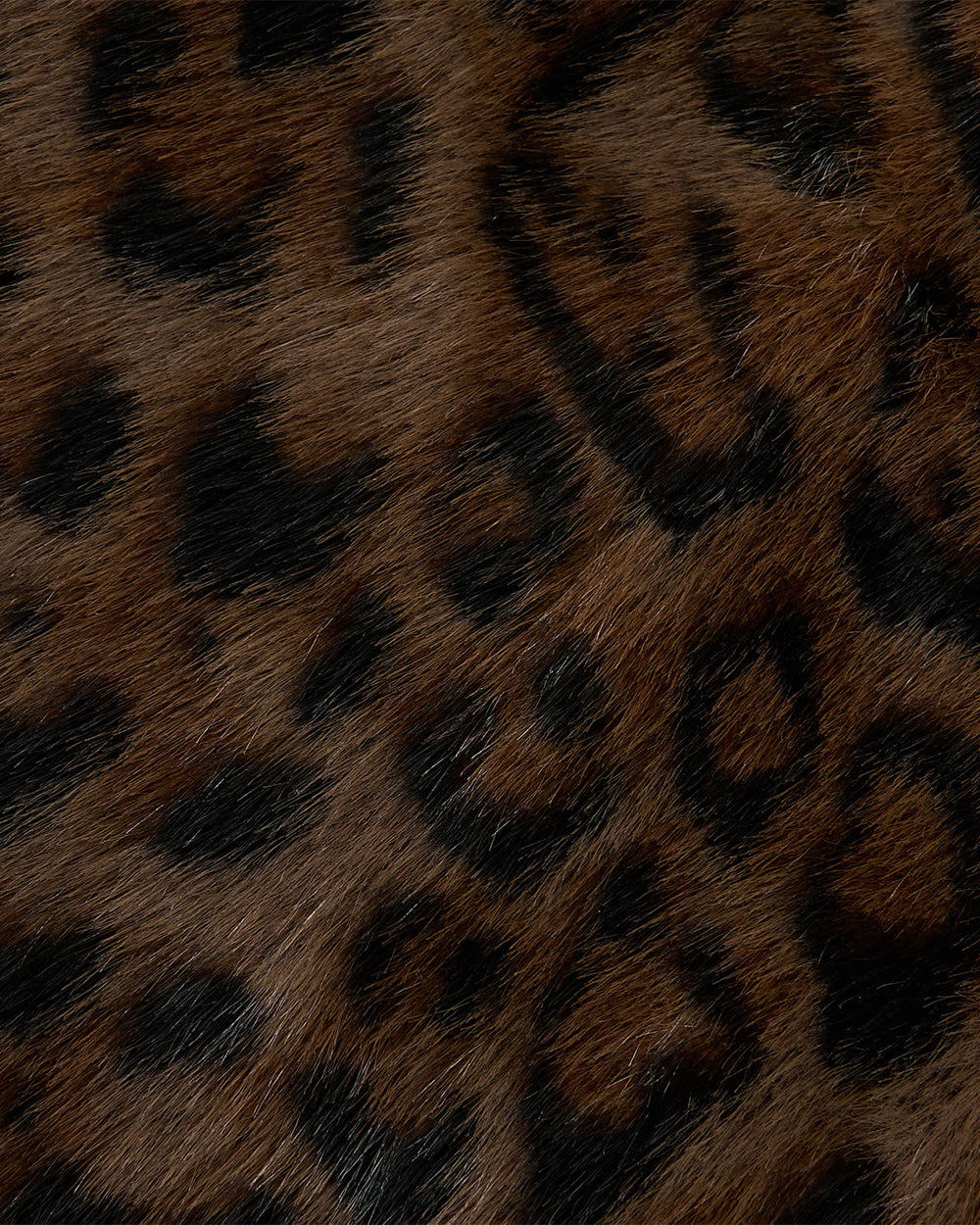 Close-up of leopard fur showing a pattern of dark brown and black rosettes on a lighter brown furry background, reminiscent of the stylish textures found in the BLACK BAEJA VEST / BAG by Sundae School.