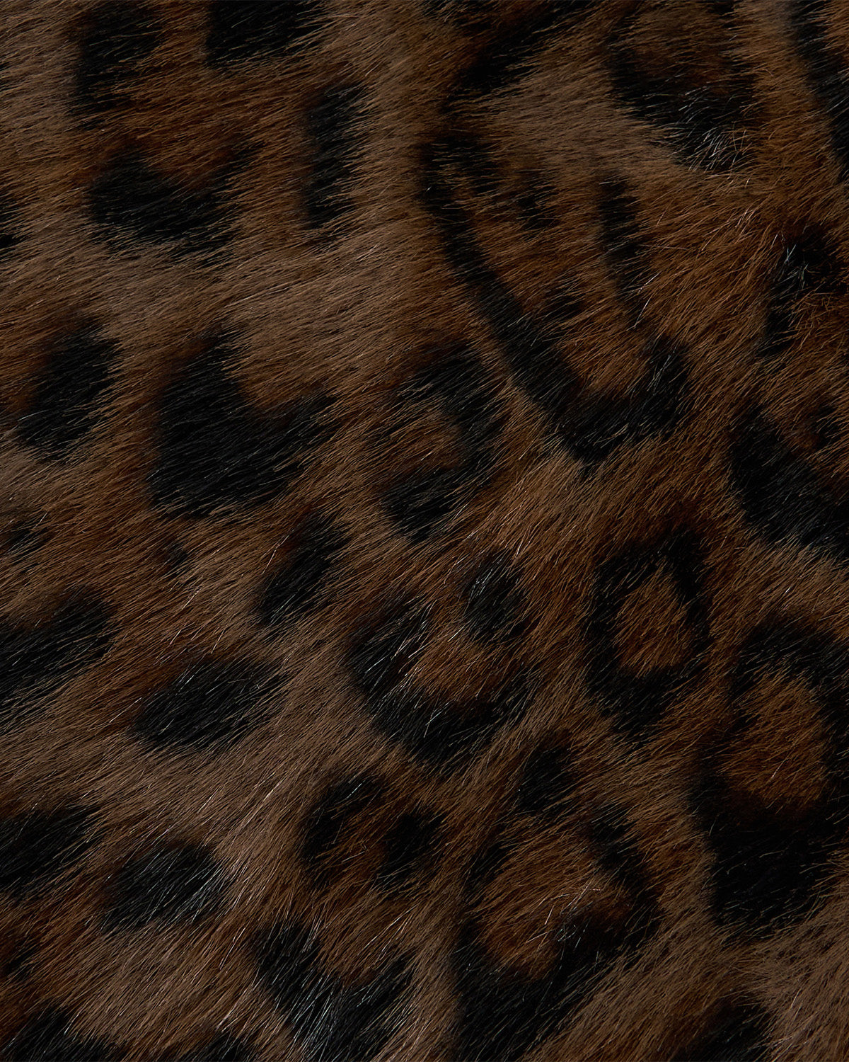Close-up of leopard fur showing a pattern of dark brown and black rosettes on a lighter brown furry background, reminiscent of the stylish textures found in the BLACK BAEJA VEST / BAG by Sundae School.