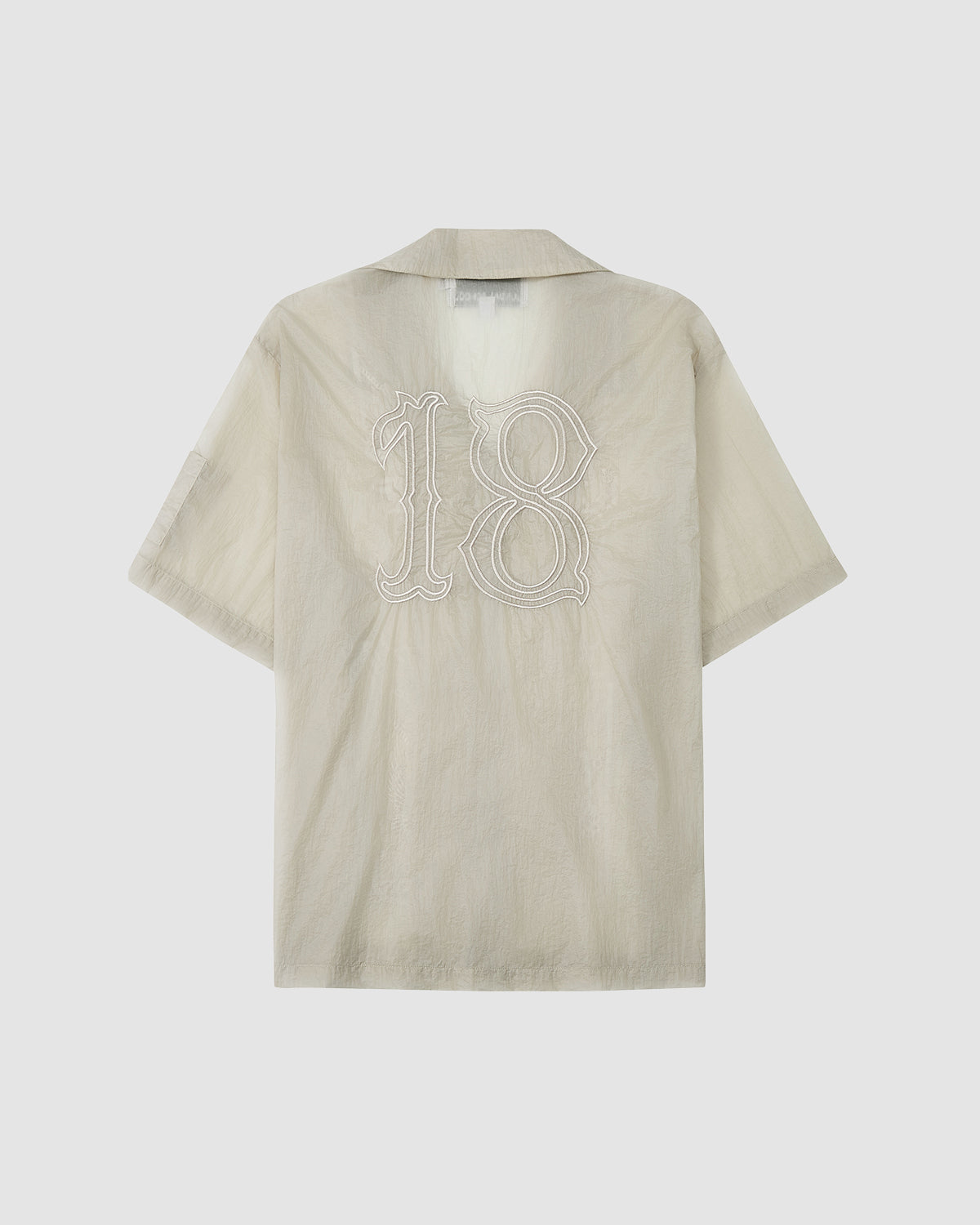 The BARONG SHIRT by Sundae School is a light beige, short-sleeve collared top with a large white outlined number 18 on the back. Inspired by the Filipino silhouette, its lightweight, slightly sheer fabric adds a modern touch.