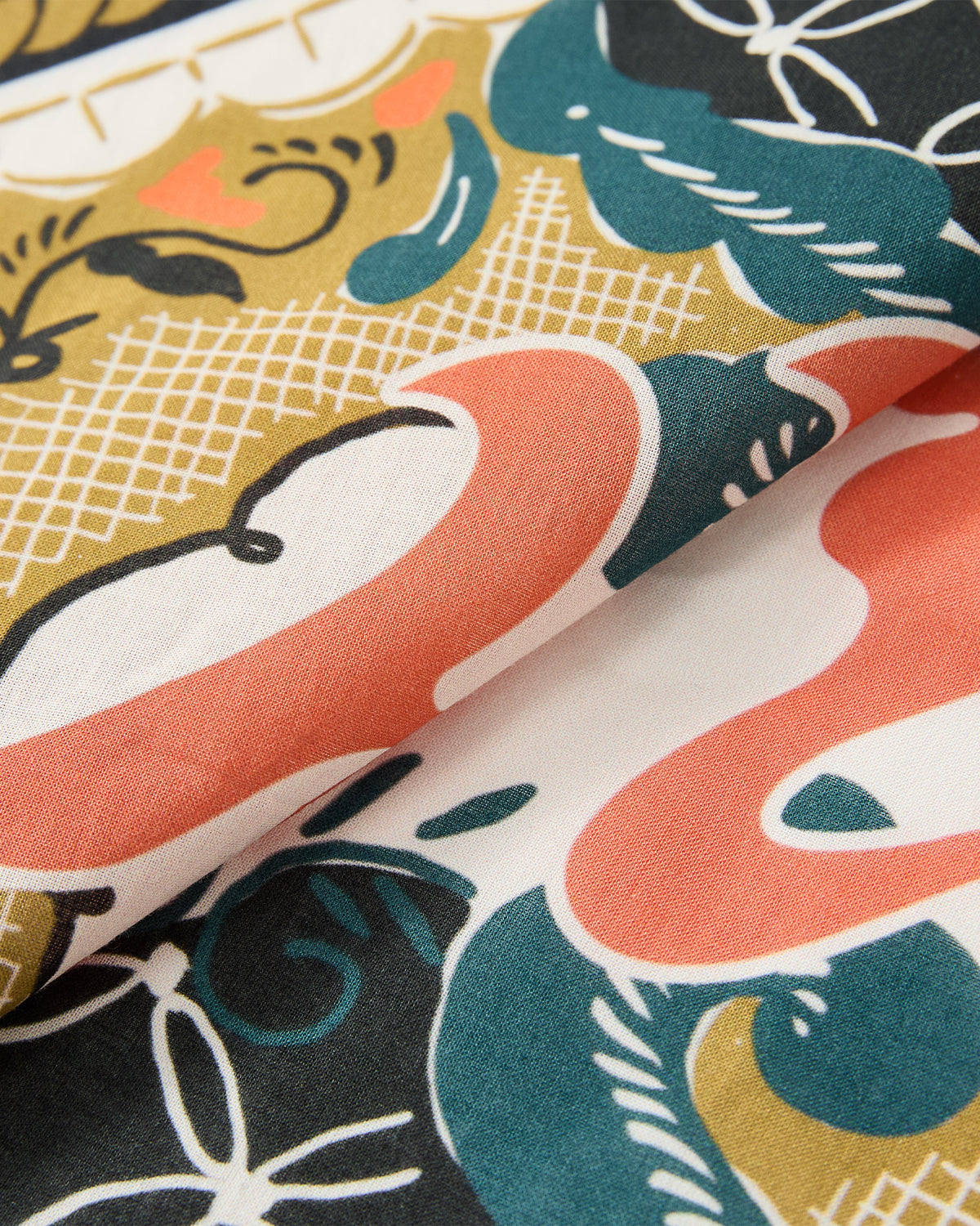 A close-up of Sundae School’s MULTI-COLOR BATIK BANDANA shows its vibrant abstract pattern, inspired by Indonesian batik, in coral, teal, black, gold, and white. Intersecting lines and folds reveal the bandana’s rich textured design.