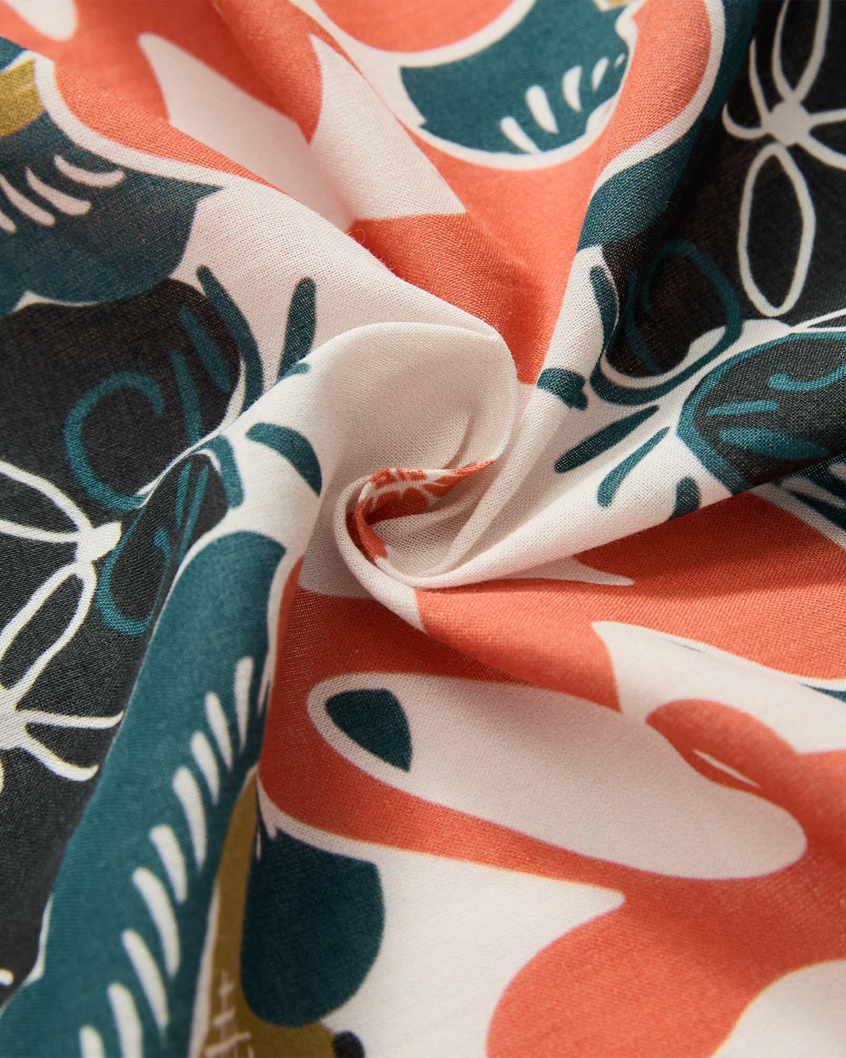 Close-up of the MULTI-COLOR BATIK BANDANA by Sundae School, featuring abstract floral and leaf patterns in coral, green, black, olive, and white, inspired by traditional Indonesian batik designs.