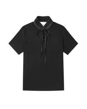 The BLACK RIBBON TIE POLO by Sundae School is a short-sleeve polo featuring a high Manchurian teardrop collar and a black ribbon tied in a bow at the neck, shown laid flat on a white background.