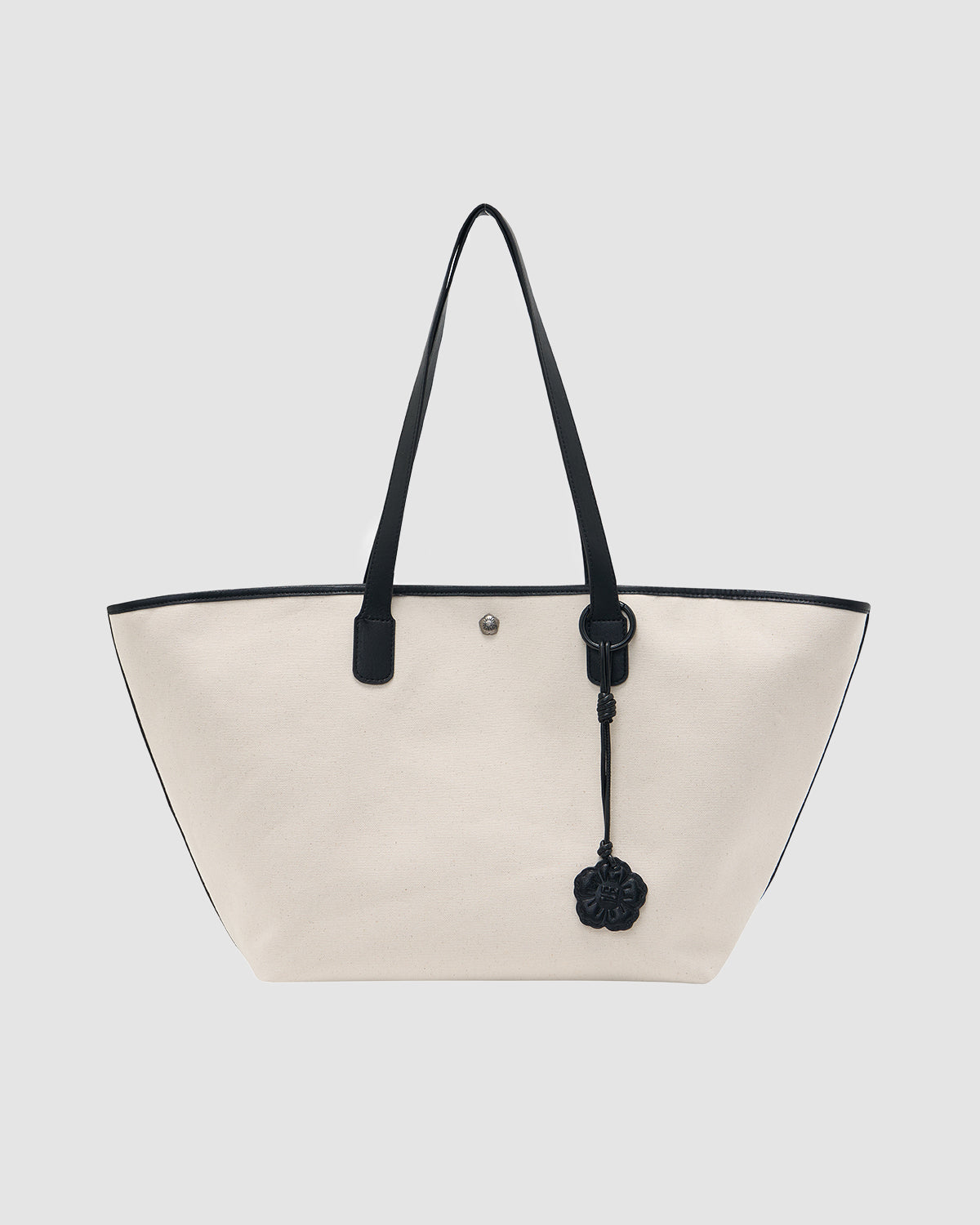 The IVORY BOJAGI TIE TOTE BAG by Sundae School is a spacious white vegan leather tote with black handles, black trim, and a decorative charm, shown against a plain light gray background.