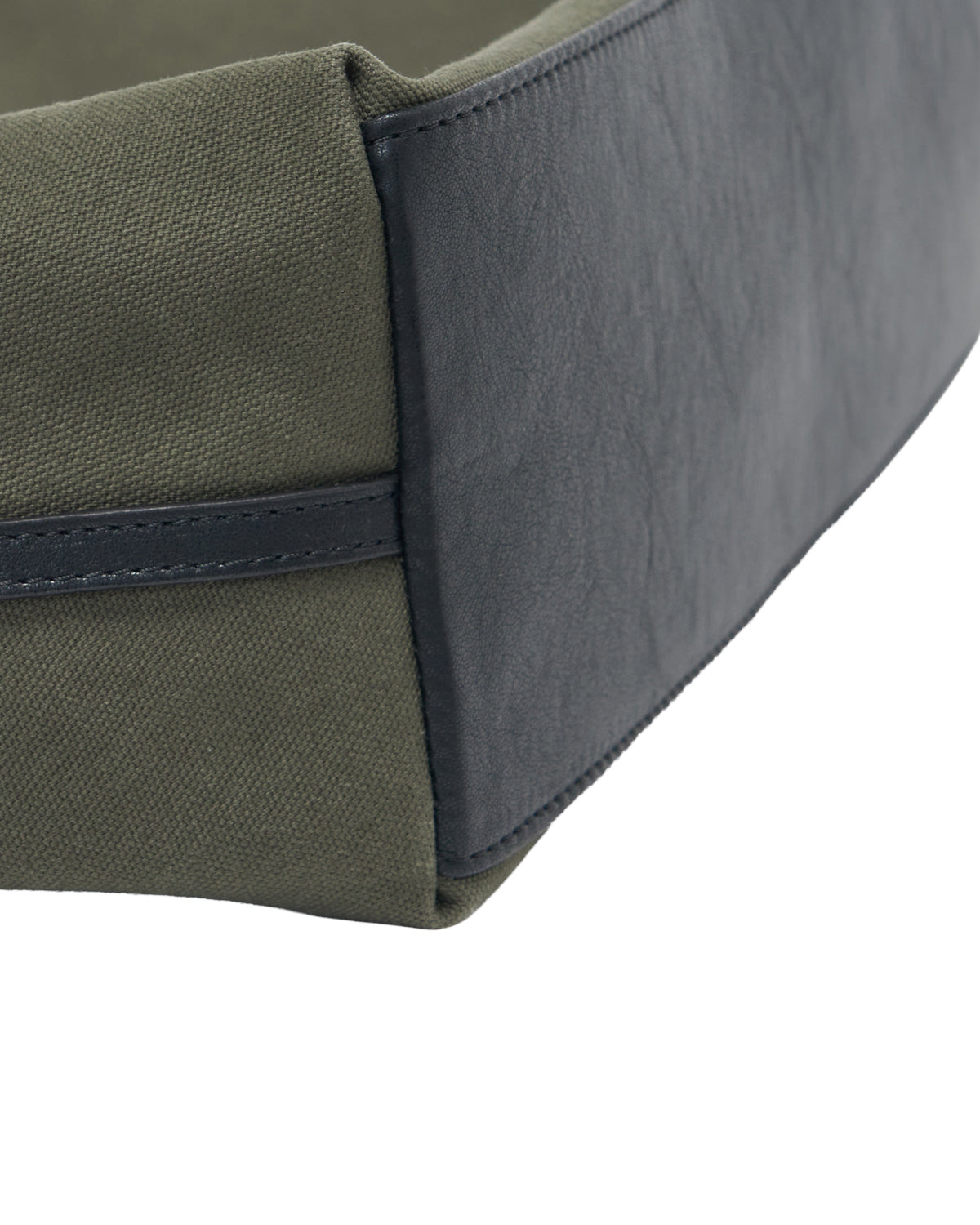 Close-up of the Sundae School OLIVE BOJAGI TIE TOTE BAG, featuring green canvas sides reminiscent of a cotton canvas bag and a black faux leather corner with visible stitching.