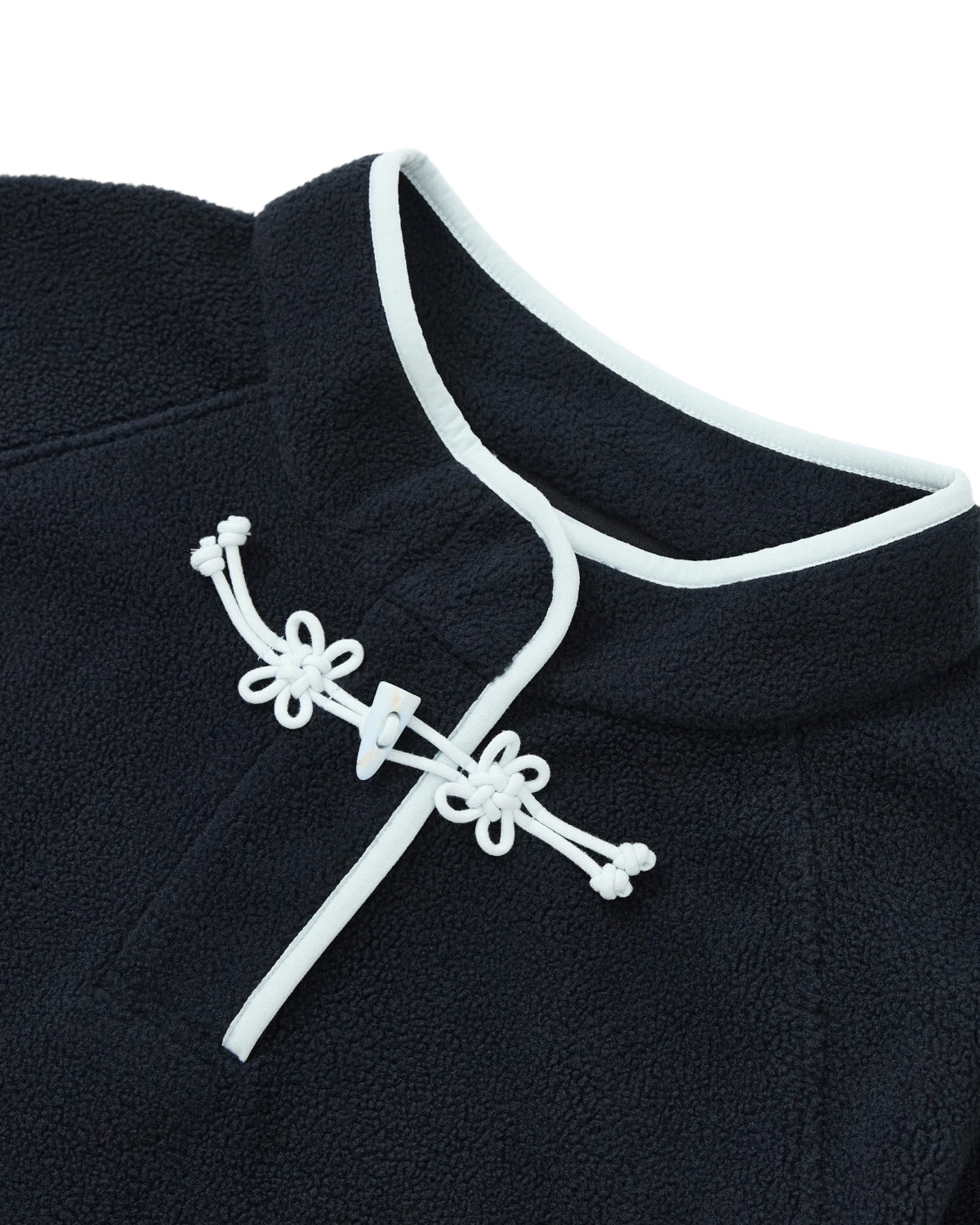 Close-up of the NAVY BUTTERFLY FLEECE PULLOVER by Sundae School, a navy blue polar fleece pullover detailed with white trim and a frog button closure at the collar, featuring decorative flower knot toggles.