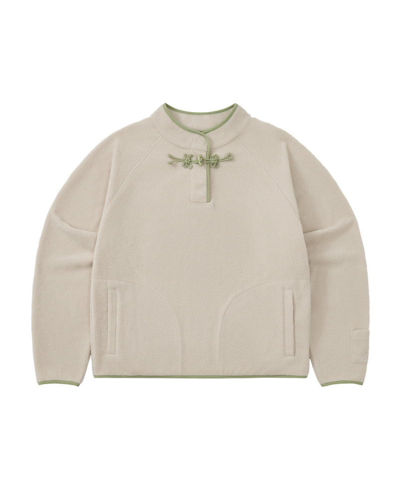 The TAUPE BUTTERFLY FLEECE PULLOVER by Sundae School is a cream-colored mock-neck polar fleece pullover with green trim, featuring a round collar adorned with hand-tied flower knots and decorative tteokbokki toggles at the neck, two front pockets, and long sleeves.