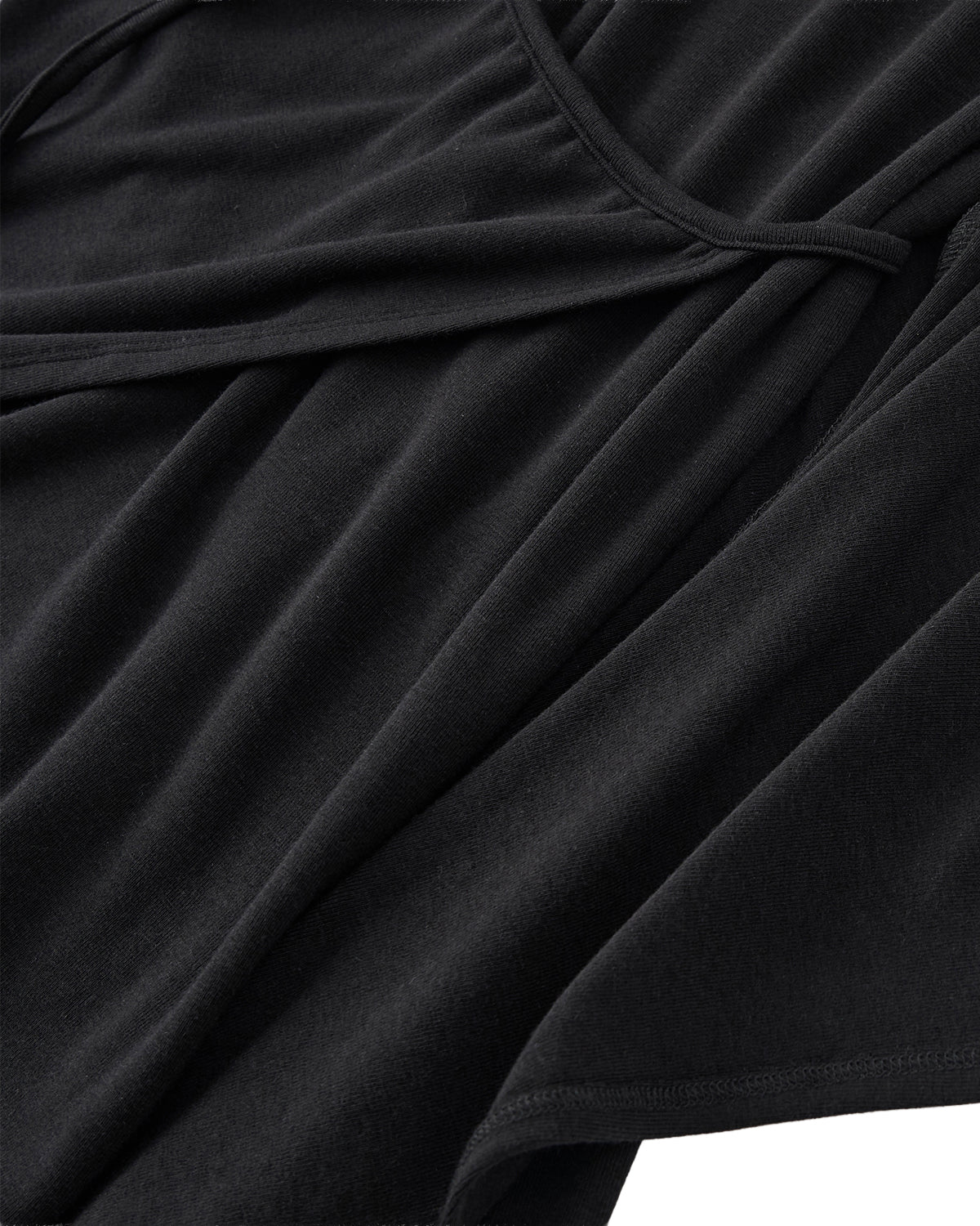 Close-up of the BLACK CINDY POLO DRESS by Sundae School, featuring black fabric with draped folds and a delicate, matching tie detail. The soft and smooth texture highlights its comfortable feel—perfect for a summer wool dress that blends elegance with relaxed ease.