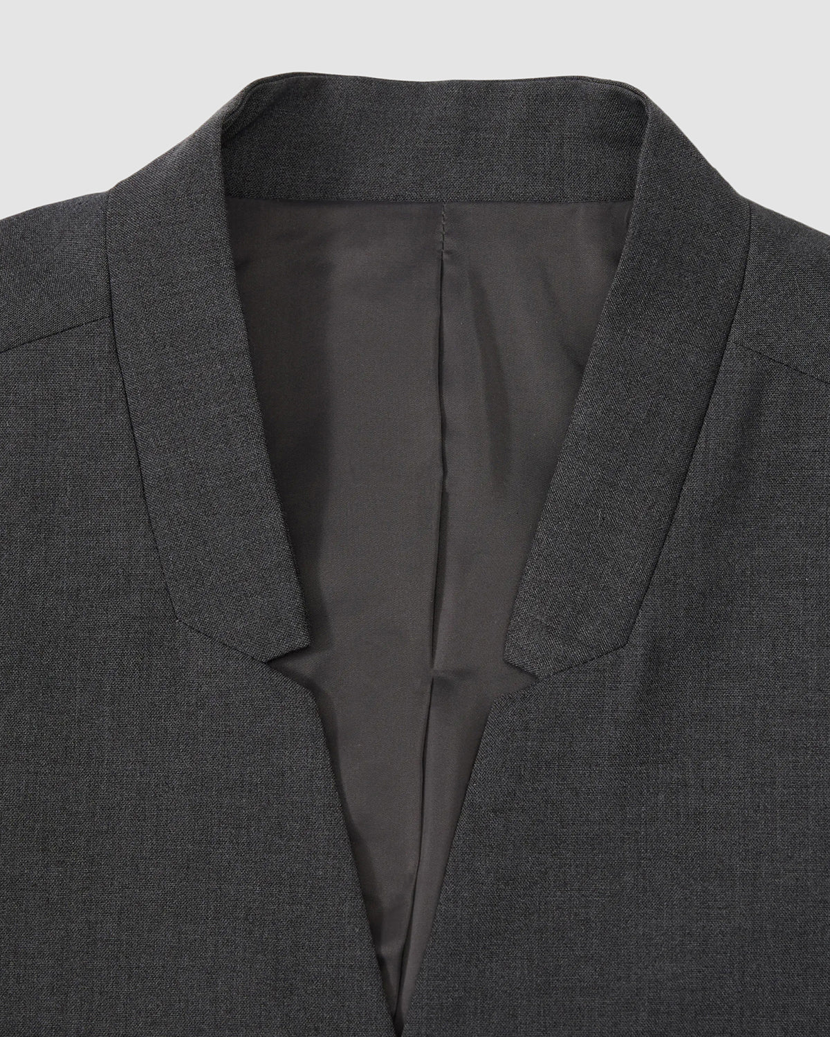 Close-up of the Sundae School COLLARLESS TIE BLAZER in dark gray, featuring a breathable design and smooth inner lining, displayed against a light gray background.
